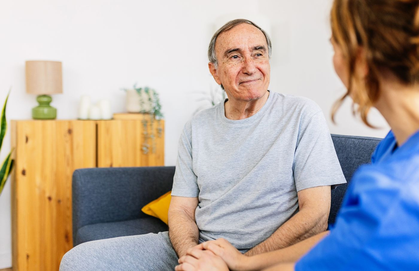 Älterer Mann im Gespräch mit einer Pflegekraft auf dem Sofa